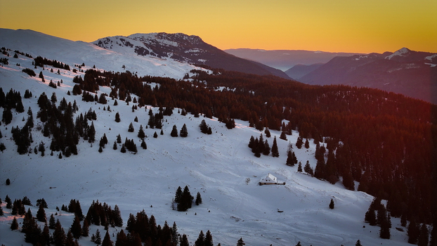 Aerial view of Col de la Faucille with snow covered slopes and pine forests under a golden sunset sky in Gex Auvergne Rhone Alpes France. Aerial view of Col de la Faucille with snow covered slopes and pine forests under a golden sunset sky in Gex Auvergne Rhone Alpes France.