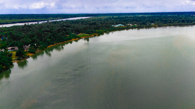 Aerial view of a wide river flowing through lush tropical forests and dense vegetation in Rivers Nigeria.