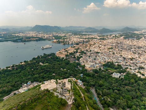 Aerial view of the historic city of Udaipur with Lake Pichola the iconic City Palace and lush surrounding hills in Udaipur Rajasthan India. Aerial view of the historic city of Udaipur with Lake Pichola the iconic City Palace and lush surrounding hills in Udaipur Rajasthan India.