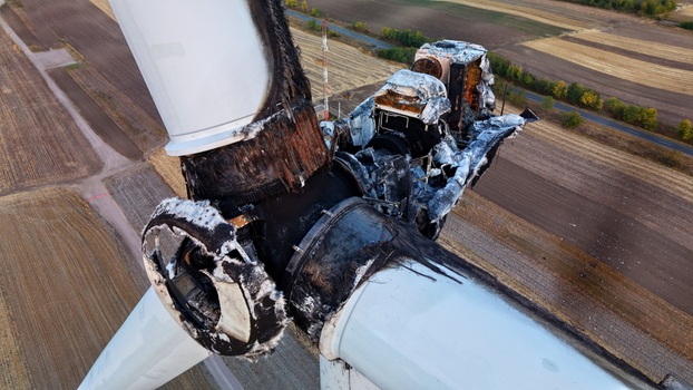 Aerial view of a severely damaged and charred wind turbine hub with burnt blades surrounded by agricultural fields in Vladimirovac Vojvodina Serbia.