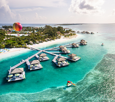 The Bahamas 10 September 2021 Aerial view of CocoCay featuring overwater cabanas turquoise waters white sandy beaches and a colorful hot air balloon in the sky.