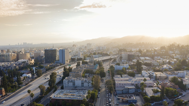 Aerial view of the urban landscape of Los Angeles with a busy freeway residential buildings and distant hills under a warm golden hour sky in Los Angeles California United States.