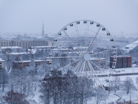 Aerial view of the Ferris wheel surrounded by snow covered trees and urban buildings in Riga Latvia. Aerial view of the Ferris wheel surrounded by snow covered trees and urban buildings in Riga Latvia.