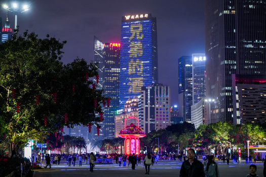 Guangzhou China 23 February 2024 View of the illuminated skyline at night featuring modern skyscrapers with festive LED displays red lanterns and people walking in the urban park. Guangzhou China 23 February 2024 View of the illuminated skyline at night featuring modern skyscrapers with festive LED displays red lanterns and people walking in the urban park.