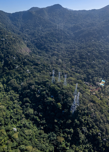 Aerial view of Parque Florestal da Tijuca featuring high voltage power transmission towers rising above the dense tropical forest canopy in Rio de Janeiro State of Rio de Janeiro Brazil.