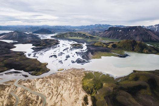 Aerial view of the intricate braided glacial rivers flowing through volcanic mountains and green mossy hills along the F208 road Icelandic Highlands Iceland. Aerial view of the intricate braided glacial rivers flowing through volcanic mountains and green mossy hills along the F208 road Icelandic Highlands Iceland.