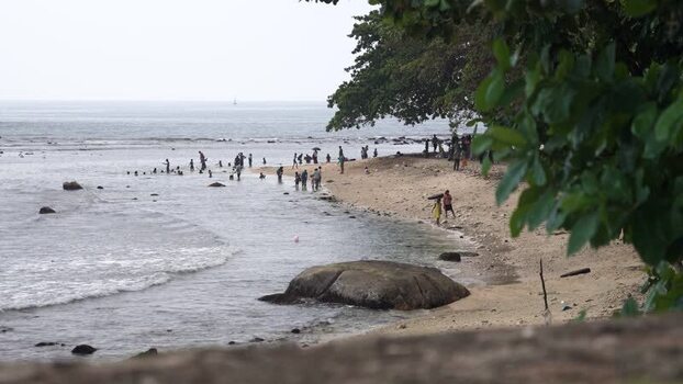 View of people enjoying a sandy beach with large rocks Sri Lanka. View of people enjoying a sandy beach with large rocks Sri Lanka.