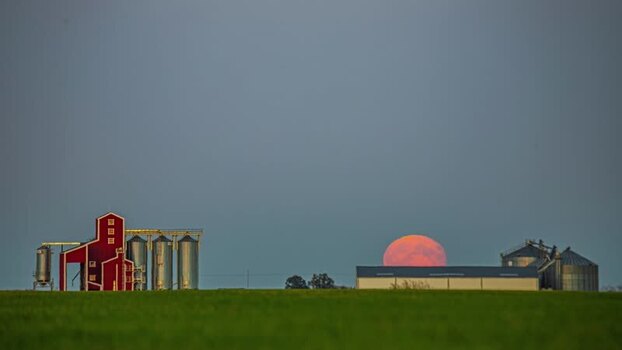View of a red moon rising over a farm in Latvia.