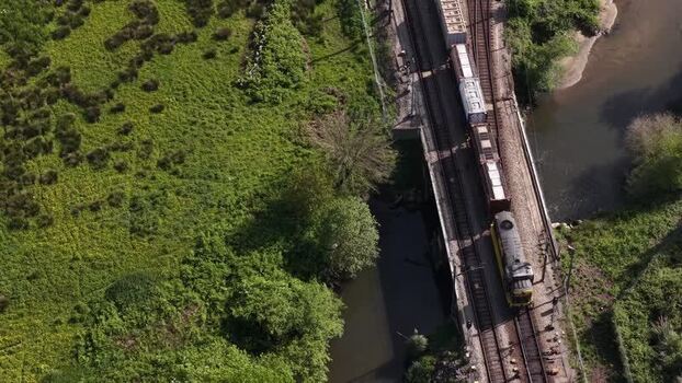 Aerial view of train carrying shipping containers on tracks near river Portugal.