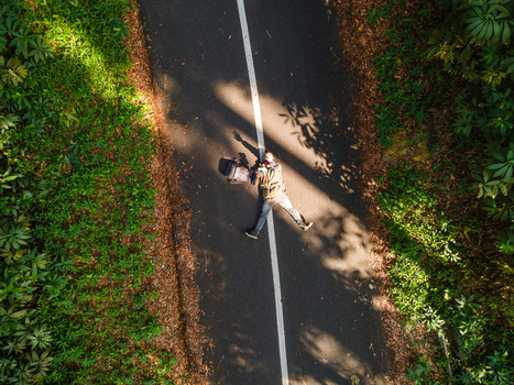 Aerial view of a person lying on a paved road with a backpack in a lush forest in Baturaden Central Java Indonesia.