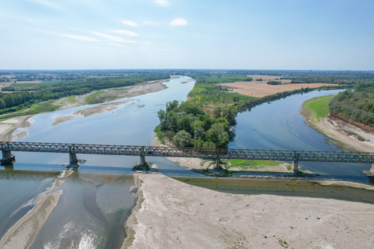 Aerial view of Ponte della Becca spanning the confluence of the Po and Ticino rivers with sandy banks and lush vegetation under a clear sky Linarolo Lombardia Italy.