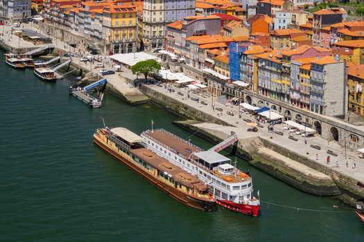 Aerial view of boats docked along the Douro River lined with colorful buildings and bustling with activity Porto Porto District Portugal. Aerial view of boats docked along the Douro River lined with colorful buildings and bustling with activity Porto Porto District Portugal.