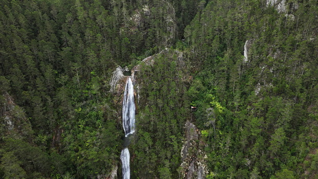 Aerial view of Salto de Aguas Blancas waterfall cascading through a dense pine forest in the mountains of Constanza La Vega Province Dominican Republic. Aerial view of Salto de Aguas Blancas waterfall cascading through a dense pine forest in the mountains of Constanza La Vega Province Dominican Republic.