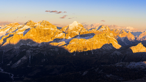 Aerial view of golden light washing over the Dolomites peaks of the rugged mountains casting dramatic shadows across the landscape Badia Valley Veneto Italy.