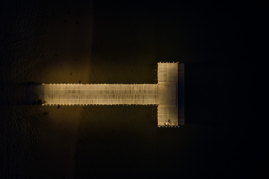 Aerial view of an illuminated wooden pier at night with glowing lights extending into the dark sea Mauritius Moka District Mauritius. Aerial view of an illuminated wooden pier at night with glowing lights extending into the dark sea Mauritius Moka District Mauritius.