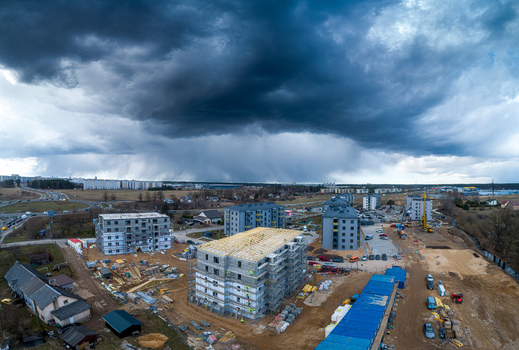 Aerial view of a residential construction site with multiple apartment buildings under development surrounded by open land and a dramatic stormy sky in Latvia. Aerial view of a residential construction site with multiple apartment buildings under development surrounded by open land and a dramatic stormy sky in Latvia.
