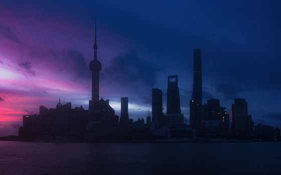 View of the Shanghai skyline featuring the Oriental Pearl Tower silhouetted against a vibrant purple and pink twilight sky over the Huangpu River in Shanghai Shanghai China.