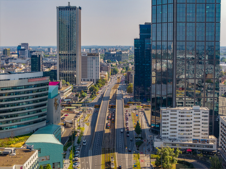 Aerial view of modern skyscrapers with glass facades and a busy multi lane road with tram tracks and traffic under a clear sky in Poland. Aerial view of modern skyscrapers with glass facades and a busy multi lane road with tram tracks and traffic under a clear sky in Poland.