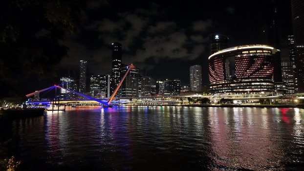 View of the illuminated Brisbane skyline and the modern Kurilpa Bridge reflecting on the Brisbane River at night in Brisbane Queensland Australia. View of the illuminated Brisbane skyline and the modern Kurilpa Bridge reflecting on the Brisbane River at night in Brisbane Queensland Australia.