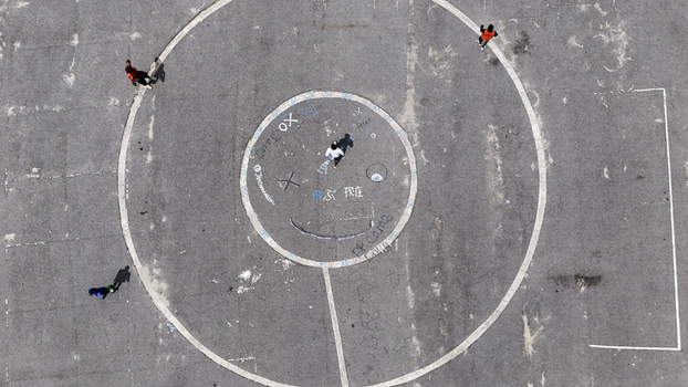 Aerial view of people walking on a concrete sports court with circular markings and a smiley face at the National Stadium Surulere Lagos Lagos Lagos Nigeria. Aerial view of people walking on a concrete sports court with circular markings and a smiley face at the National Stadium Surulere Lagos Lagos Lagos Nigeria.