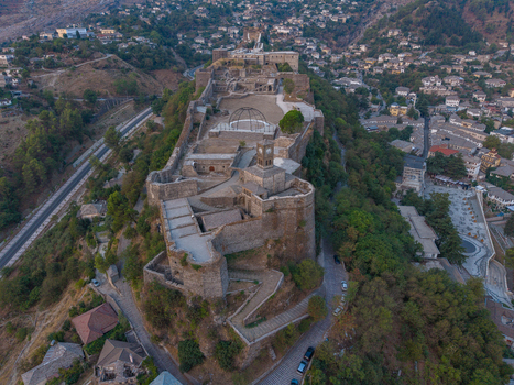 Aerial view of Gjirokaster Fortress a historic stone citadel overlooking the traditional Ottoman style houses and winding streets of the old town in Gjirokaster Gjirokaster County Albania. Aerial view of Gjirokaster Fortress a historic stone citadel overlooking the traditional Ottoman style houses and winding streets of the old town in Gjirokaster Gjirokaster County Albania.