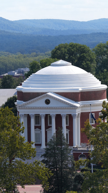 Aerial view of The Rotunda at the University of Virginia with its white dome and red brick facade surrounded by trees and the Blue Ridge Mountains in Charlottesville Virginia United States.