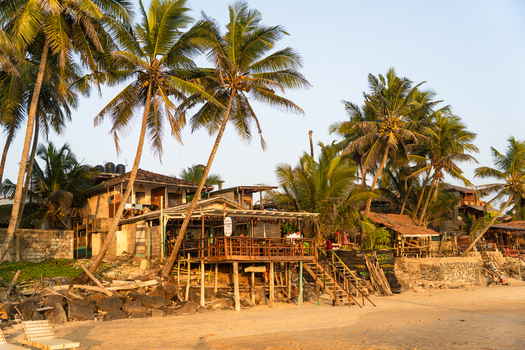 View of a beachfront restaurant with people on a wooden terrace nestled among tall palm trees on a sandy shore under a clear sky Galle Southern Province Sri Lanka.