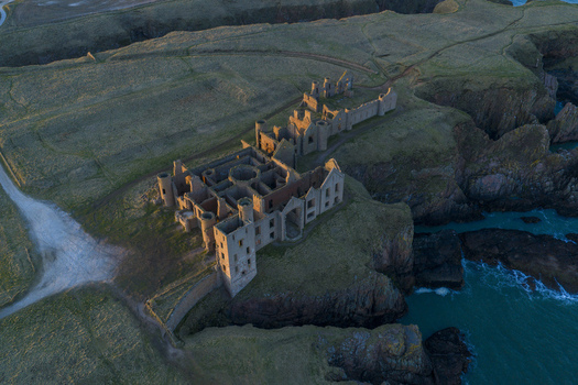 Aerial view of Slains Castle ruins on the rugged cliffs of the North Sea coast during golden hour Cruden Bay Scotland United Kingdom. Aerial view of Slains Castle ruins on the rugged cliffs of the North Sea coast during golden hour Cruden Bay Scotland United Kingdom.