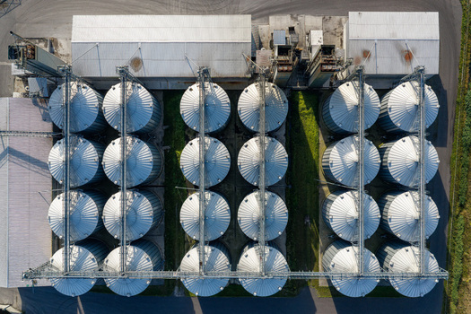 Aerial view of large grain bins arranged in rows at a storage facility in Poland.