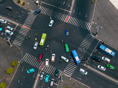 Aerial view of a busy urban intersection with numerous cars buses and motorbikes navigating through marked crosswalks on asphalt roads in Vietnam. Aerial view of a busy urban intersection with numerous cars buses and motorbikes navigating through marked crosswalks on asphalt roads in Vietnam.