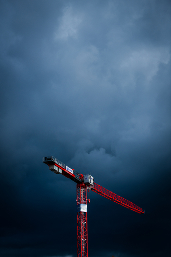 Zurich Switzerland 02 April 2023 View of a construction crane piercing the dramatic brooding sky its red frame a stark contrast to the swirling dark clouds above. Zurich Switzerland 02 April 2023 View of a construction crane piercing the dramatic brooding sky its red frame a stark contrast to the swirling dark clouds above.