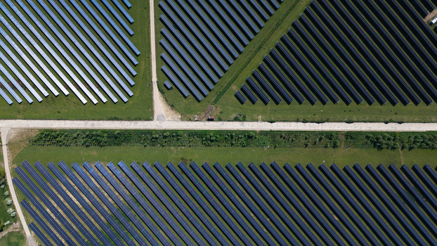 Aerial view of the solar panels at Chelveston Renewable Energy Park arranged in geometric rows across green fields with intersecting access roads Wellingborough England United Kingdom. Aerial view of the solar panels at Chelveston Renewable Energy Park arranged in geometric rows across green fields with intersecting access roads Wellingborough England United Kingdom.