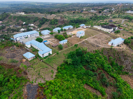 Aerial view of buildings nestled among rolling hills where structures with light blue roofs contrast against the verdant landscape Ohafia Abia Nigeria. Aerial view of buildings nestled among rolling hills where structures with light blue roofs contrast against the verdant landscape Ohafia Abia Nigeria.