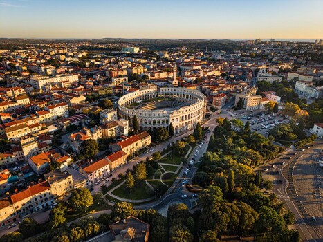 Aerial view of the magnificent Pula Arena bathed in golden sunlight a testament to ancient Roman architecture surrounded by the vibrant cityscape Pula Istria County Croatia.