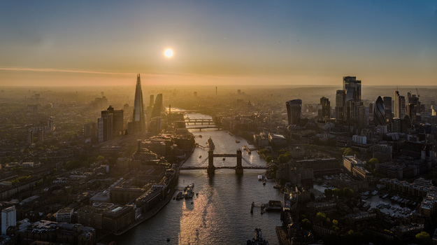Aerial view of Tower Bridge spanning the River Thames with the Shard and city skyscrapers under a golden sunset in London Greater London United Kingdom. Aerial view of Tower Bridge spanning the River Thames with the Shard and city skyscrapers under a golden sunset in London Greater London United Kingdom.