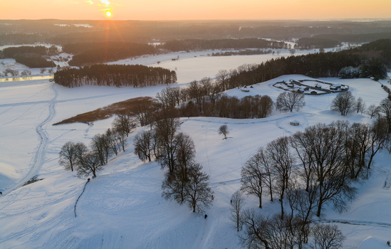Aerial view of the snow covered mounds and wooden fortifications at the Kernave Archaeological Site during a golden sunset Kernave Vilnius County Lithuania.