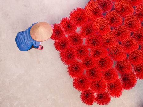 Aerial view of a person in a conical hat arranging vibrant red incense bundles on a concrete surface in Vietnam. Aerial view of a person in a conical hat arranging vibrant red incense bundles on a concrete surface in Vietnam.