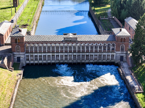 Aerial view of the historic Canale Cavour intake building with rushing water and arched windows Chivasso Piedmont Italy.