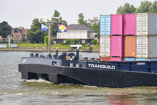 Dordrecht Netherlands 31 May 2026 View of the inland container ship Tranquilo navigating the Oude Maas river with colorful cargo containers stacked on deck.