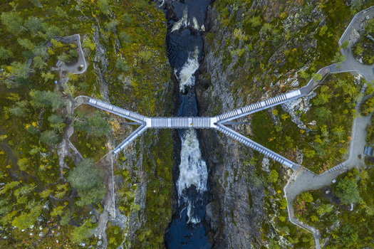 Aerial view of the modern Voringfossen bridge spanning a deep rocky gorge with rushing water below in Eidfjord Municipality Vestland Norway.