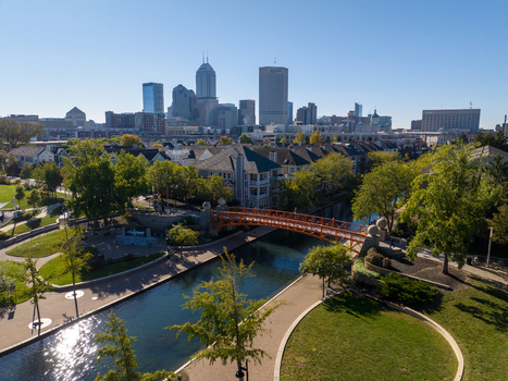Aerial view of the Indianapolis Central Canal and skyline with a pedestrian bridge lush trees and urban architecture in Indianapolis Indiana United States. Aerial view of the Indianapolis Central Canal and skyline with a pedestrian bridge lush trees and urban architecture in Indianapolis Indiana United States.