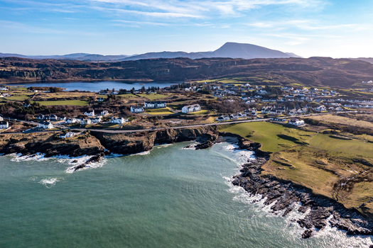 Aerial view of the coastal village of Portnablagh featuring rocky cliffs green pastures and residential houses along the shoreline in Portnablagh County Donegal Ireland. Aerial view of the coastal village of Portnablagh featuring rocky cliffs green pastures and residential houses along the shoreline in Portnablagh County Donegal Ireland.