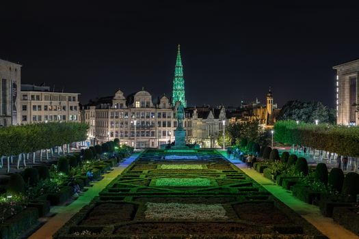View of the formal gardens at Mont des Arts with the illuminated spire of the Brussels Town Hall and historic architecture at night Brussels Brussels Belgium.