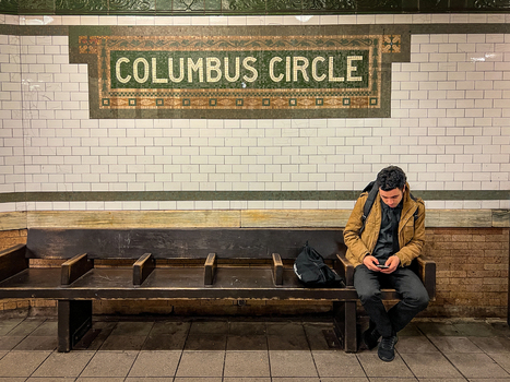 New York United States 14 May 2026 View of a man sitting on a wooden bench looking at his phone in front of the Columbus Circle mosaic sign in a subway station. New York United States 14 May 2026 View of a man sitting on a wooden bench looking at his phone in front of the Columbus Circle mosaic sign in a subway station.