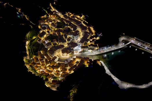 Aerial view of the illuminated coastal village at night with warm streetlights reflecting on the historic houses and the harbor pier Cudillero Asturias Spain. Aerial view of the illuminated coastal village at night with warm streetlights reflecting on the historic houses and the harbor pier Cudillero Asturias Spain.