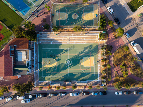 Glyfada Greece 12 June 2026 Aerial view of outdoor basketball courts with people playing surrounded by urban streets parked cars and green trees.