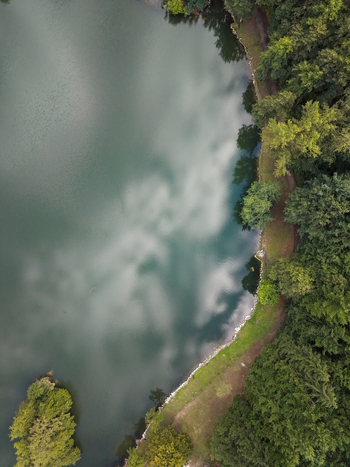 Aerial view of Lago Pontini with cloud reflections on the water surface surrounded by dense forest in Bagno di Romagna Emilia Romagna Italy. Aerial view of Lago Pontini with cloud reflections on the water surface surrounded by dense forest in Bagno di Romagna Emilia Romagna Italy.