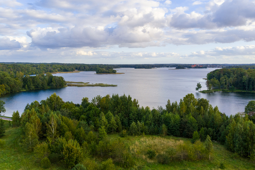 Aerial view of tranquil lake surrounded by lush green forests and small islands under a soft cloudy sky Lithuania. Aerial view of tranquil lake surrounded by lush green forests and small islands under a soft cloudy sky Lithuania.