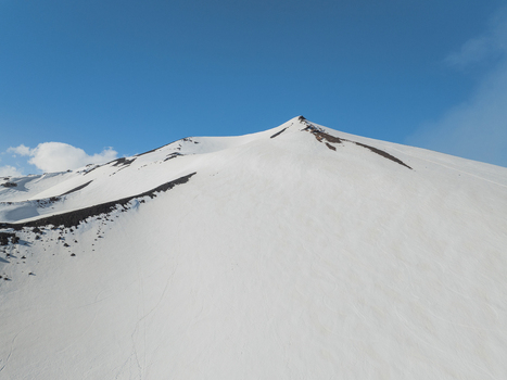 Aerial view of the snow covered south slope of Mount Etna with volcanic rock ridges under a clear blue sky in Nicolosi Sicilia Italy. Aerial view of the snow covered south slope of Mount Etna with volcanic rock ridges under a clear blue sky in Nicolosi Sicilia Italy.