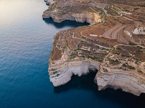Aerial view of rugged cliffs meeting the deep blue sea at Sanap Cliffs contrasting with the terraced landscape above Munxar Gozo Malta. Aerial view of rugged cliffs meeting the deep blue sea at Sanap Cliffs contrasting with the terraced landscape above Munxar Gozo Malta.
